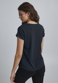 Dunkelblaues T-Shirt mit kurzen Ärmeln und umgeschlagenen Bündchen, aus weichem Baumwollstoff, lockerer Passform und rundem Ausschnitt, mit minimalistischem Design.