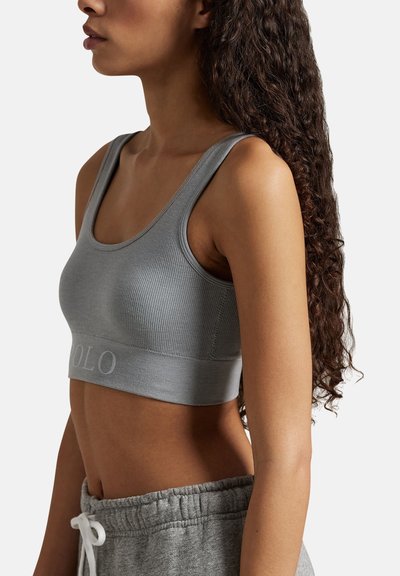 Grå ribbad crop top med en bred band med broderad logotyp, kombinerad med grå sweatpants med dragsko. Slät textur, atletisk design.