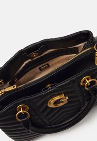 Schwarze gesteppte Lederhandtasche mit goldfarbenen Beschlägen, die innen mehrere Reißverschluss- und Steckfächer sowie ein auffälliges Logo auf der Vorderseite aufweist.