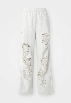 Pantalons de survêtement gris clair avec une coupe ample, comportant plusieurs patches déchirés, une texture douce et une taille élastique.
