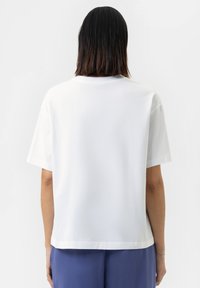 Witte katoenen t-shirt met een ontspannen pasvorm, korte mouwen en een ronde hals, met een naadloos ontwerp aan de achterkant.