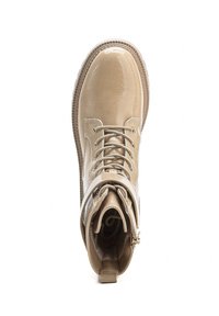 Botte de cheville en cuir verni beige avec un bout rond, un système de laçage à l'avant et une fermeture éclair sur le côté, dotée d'une finition texturée et d'une semelle contrastante.