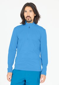 Lysblå langærmet pullover med høj krave og kvart lynlås, lavet af glat, strækbart stof, parret med teal shorts.