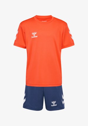 Jersey deportivo naranja de manga corta, con un logo y detalles en blanco. Combinado con shorts azul marino, ambos de tela ligera.
