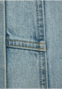 Tessuto in denim azzurro chiaro con un motivo a rovescio diagonale, caratterizzato da cuciture gialle e un piccolo dettaglio della tasca sul bordo.