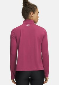 Long-sleeve pullover top in deep pink fabric with a high collar and elastic cuffs. Features a logo on the upper back, smooth texture.