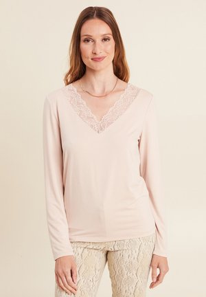 Top a maniche lunghe, rosa chiaro, con scollatura a V realizzato in tessuto morbido con bordino in pizzo sul colletto. Texture liscia, vestibilità casual e dettagli minimi.