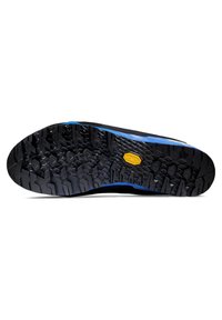 Czarna gumowa podeszwa buta z teksturowanym wzorem, z heksagonalnymi i zygzakowymi motywami. Niebieski akcent biegnie wzdłuż krawędzi. Widoczne logo Vibram.