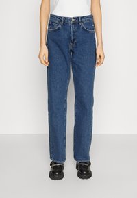 Jeans de denim en azul oscuro con corte recto. Presenta bolsillos delanteros, trabillas para el cinturón y un cierre de botón y cremallera. Tejido texturizado.