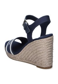 Sandalia cuña azul marino con suela de yute estilo espadrille, tira ajustable en el tobillo y franja decorativa blanca en contraste.