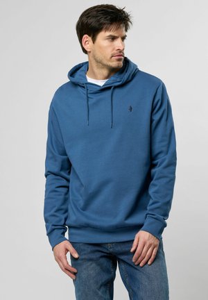 Sudadera con capucha en azul profundo, con bolsillo tipo canguro, puños acanalados y un pequeño logo en el pecho. El material parece suave y texturizado.