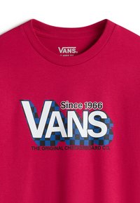Punainen puuvillapaita, jossa on pyöreä kaula-aukko ja klassinen malli. Paidassa on valkoinen "VANS"-logo ja sinivalkoinen ruutukuosi sekä teksti "Since 1966."