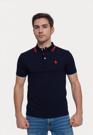 Marineblå polo-shirt med røde og hvide detaljer, med krave og logo. Den har korte ærmer og en slim fit design.