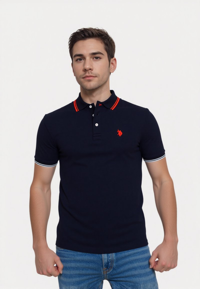 Námořnická modrá polokošile s červenými a bílými akcenty, vybavená límcem a logem. Má krátké rukávy a úzký střih.