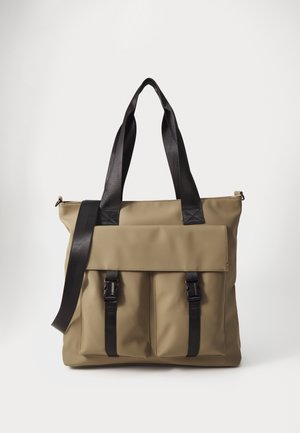 Sac fourre-tout kaki en matériau durable, doté de deux anses noires, d’un rabat pliant avec des détails à boucle, et de deux poches frontales.