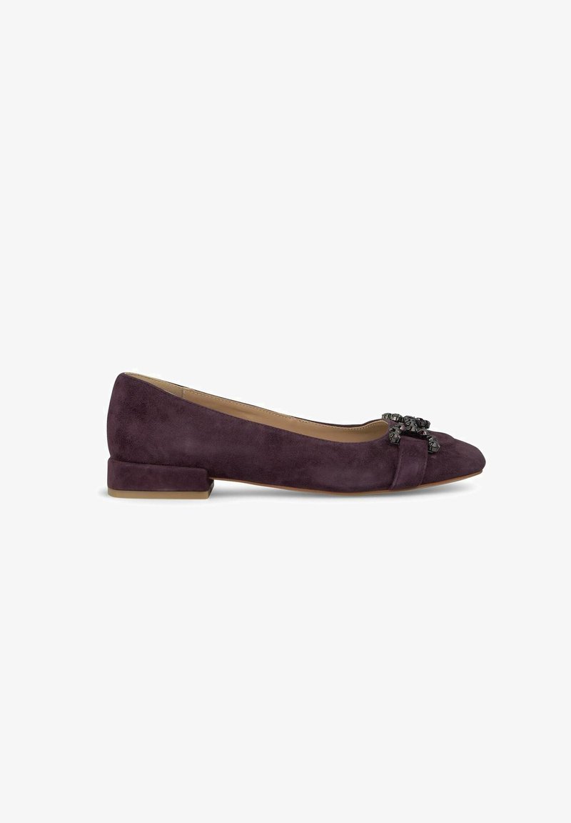 Scarpa piatta in suede viola con tacco basso a blocco, punta affusolata e fiocco decorativo con accenti neri nella parte anteriore. Texture liscia in tutto il suo aspetto.