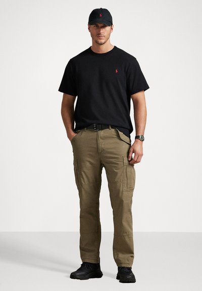 Μαύρο βαμβακερό μπλουζάκι με μικρό κόκκινο λογότυπο, χακί cargo παντελόνι με τσέπες, μαύρη ζώνη και μαύρα παπούτσια, συμπληρωμένο με συνδυασμένο καπέλο.