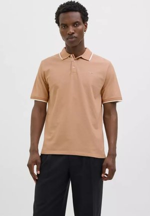 Polo shirt marron clair avec un plastron à trois boutons, col et bordures de manches blancs contrastants, et logo discret sur la poitrine. Texture unie.