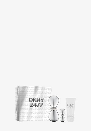 Coffret cadeau parfum DKNY 24/7 avec deux flacons argentés en forme de sablier et un tube de lotion corporelle blanc à côté d’une boîte blanche avec texte répété.