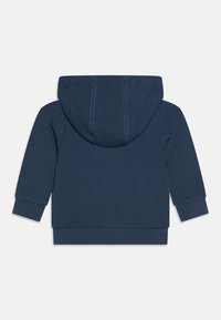 Námořnická modrá mikina s kapucí vyrobená z bavlněné směsi. Má žebrované manžety, lem a kontrastní modré prošívání na kapuci.