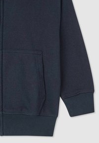 Felpa con zip di colore blu navy realizzata in un tessuto morbido, dotata di tasca frontale, polsini a costine e una superficie liscia. Nessun dettaglio grafico visibile.