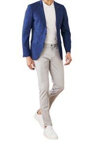 Niebieska teksturowana marynarka na jasnoszarej polówce, zestawiona z wąskimi szarymi spodniami i białymi trampkami, podkreślająca nowoczesny, casualowy wygląd.