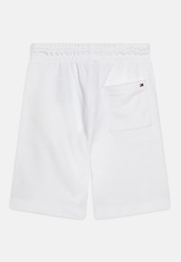 Pantaloni corti bianchi in cotone con vita elastica, dotati di una tasca posteriore e un piccolo logo decorativo. Texture liscia e design fino al ginocchio.