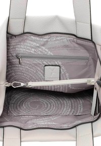 Valge tekstuuriga nahast käekott, millel on lukuga sulgur. Sisedisainis on heledat halli kangast vooder, millel on trükitud tekst ja lukuga tasku.