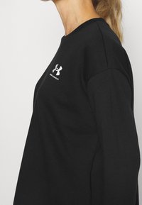 Svart sweatshirt i bomull, med rund hals och långa ärmar. Inkluderar en vit Under Armour-logotyp på bröstet. Slen textur.