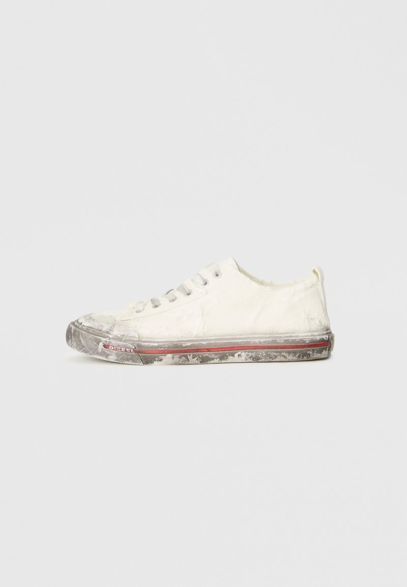 Zapatilla de lona blanca con punta redondeada, suela de goma gris y una franja de acento roja. Aspecto gastado con bordes deshilachados y una puntera parcialmente dañada.