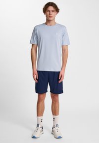 Ljusblå atletisk t-shirt, kortärmad, marinblå shorts, vita strumpor med svarta ränder, vita och blå sneakers. Slät tyg, avslappnad passform.