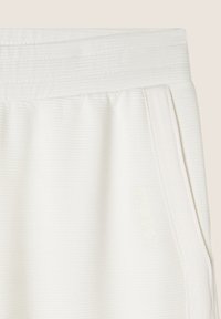 Pantaloni da tuta bianchi a coste con un cinturino testurizzato, tasche laterali e un logo in rilievo discreto che recita "FREDDY". Tessuto liscio e morbido.