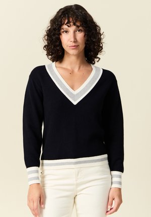 Maglione blu navy a scollo a V con righe grigio chiaro e bianche sul colletto e sui polsini. Texture morbida, design aderente, maniche lunghe e orlo a coste.