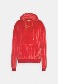 Sudadera de terciopelo rojo con bolsillo frontal tipo pouch, capucha con cordón y logo bordado en oro. Los puños y el dobladillo acanalados completan el diseño.