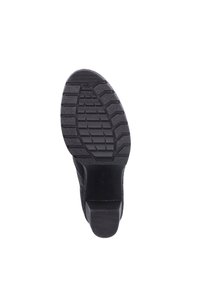 Suela de zapato de goma negra con un patrón de relieve texturizado para mayor agarre, con un talón estructurado y bordes suaves para mayor estabilidad.