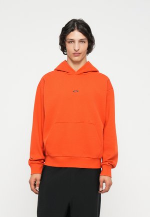 Hanorac portocaliu cu buzunar frontal, glugă ajustabilă cu șnur și accent de logo. Fabricat dintr-un material moale, având o croială lejeră.