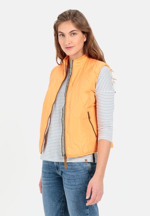 Quilted orange vest med høj krave, fuld frontlynlås og sidelommer. Bæret over en grå og hvid stribet langærmet skjorte og blå jeans.