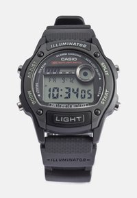 Orologio digitale nero con cinturino in plastica. Presenta un display LCD grigio, più pulsanti e un'etichetta "Illuminator" sul cinturino. Resistente all'acqua fino a 50 m.