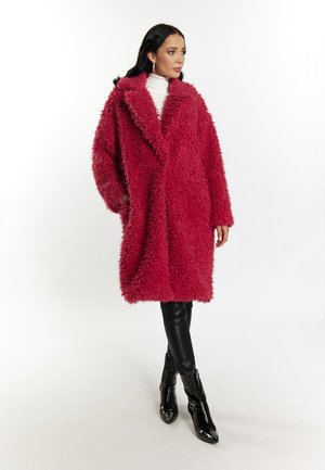 Fluffy, diep roze oversized jas met een sjawlcol en lange mouwen, en zijzakken, gecombineerd met strakke zwarte broeken en glanzende haklaarzen.