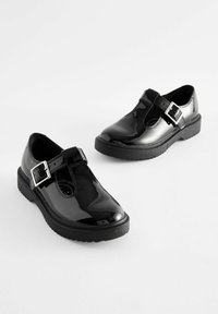 Zwarte gepatineerde leren T-strap schoenen met een ronde neus, voorzien van een vierkante gesp en een dikke zwarte rubberen zool voor extra grip.