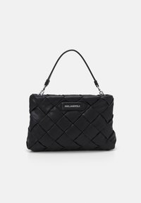 Svart kviltad läderhandväska med en slät textur, med ett kort handtag och en silverfärgad logoskylta framtill.