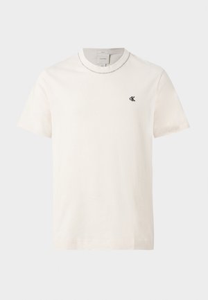 Krótkawy, kremowobiały T-shirt Calvin Klein z okrągłym dekoltem i małym czarnym logo „cK” na lewej piersi.
