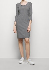 Pasiasta sukienka z okrągłym dekoltem i rękawami do trzech czwarte, wykonana z miękkiego materiału. Połączona z białymi trampkami z złotymi akcentami.