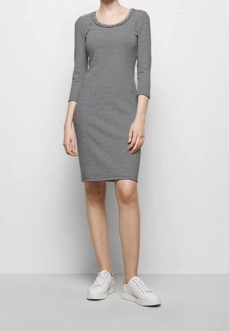 Pasiasta sukienka z okrągłym dekoltem i rękawami do trzech czwarte, wykonana z miękkiego materiału. Połączona z białymi trampkami z złotymi akcentami.