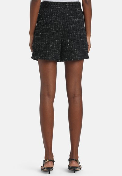 Shorts en tweed noir avec un motif texturé et des fils métalliques subtils, dotés d'une taille ajustée et d'une coupe arrivant au genou.