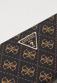 Portafoglio sintetico nero con un design a motivo dorato, contornato da accenti cuciti, e un logo dorato triangolare su una superficie texturizzata.