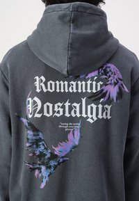 Charcoal gray hoodie featuring a graphic design with purple and black birds, bold text reading "Romantic Nostalgia," and a quote below.