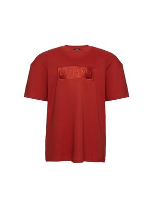 Czerwona, krótkorękawowa, luźna koszulka z wypukłą naszywką "LA MANIA" na środku klatki piersiowej.