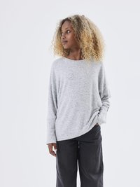 Pull gris à manches longues en tissu tricoté doux avec une coupe décontractée. Associé à un pantalon noir à jambes larges. Fond blanc uni.