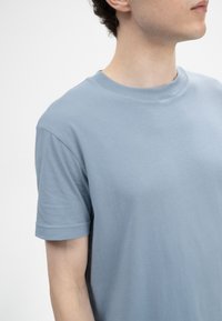 Lichtblauwe katoenen t-shirt met een ronde hals, korte mouwen en een zachte textuur. De stof lijkt glad met minimale stikdetails.